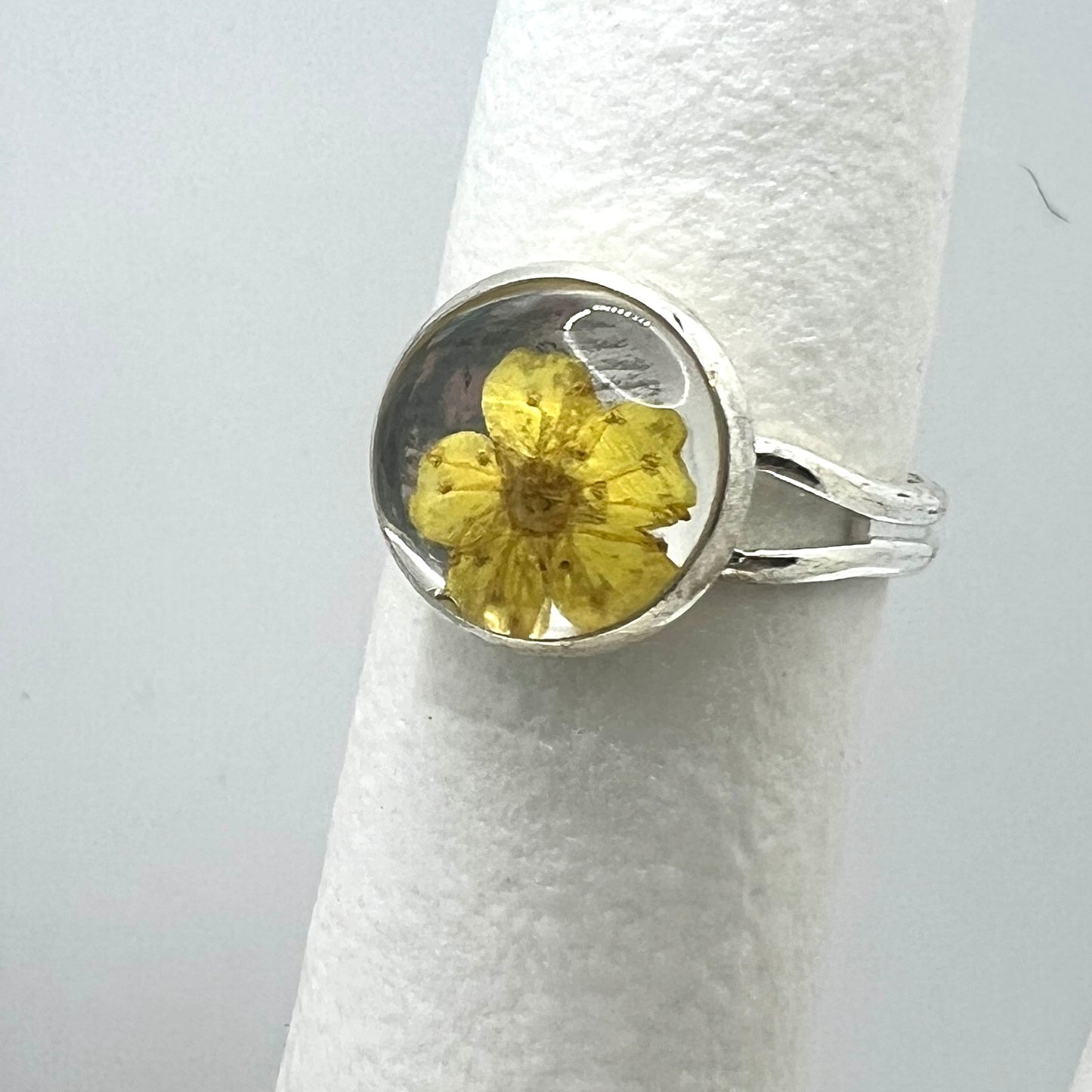Silver ring with a yellow flower on a white background